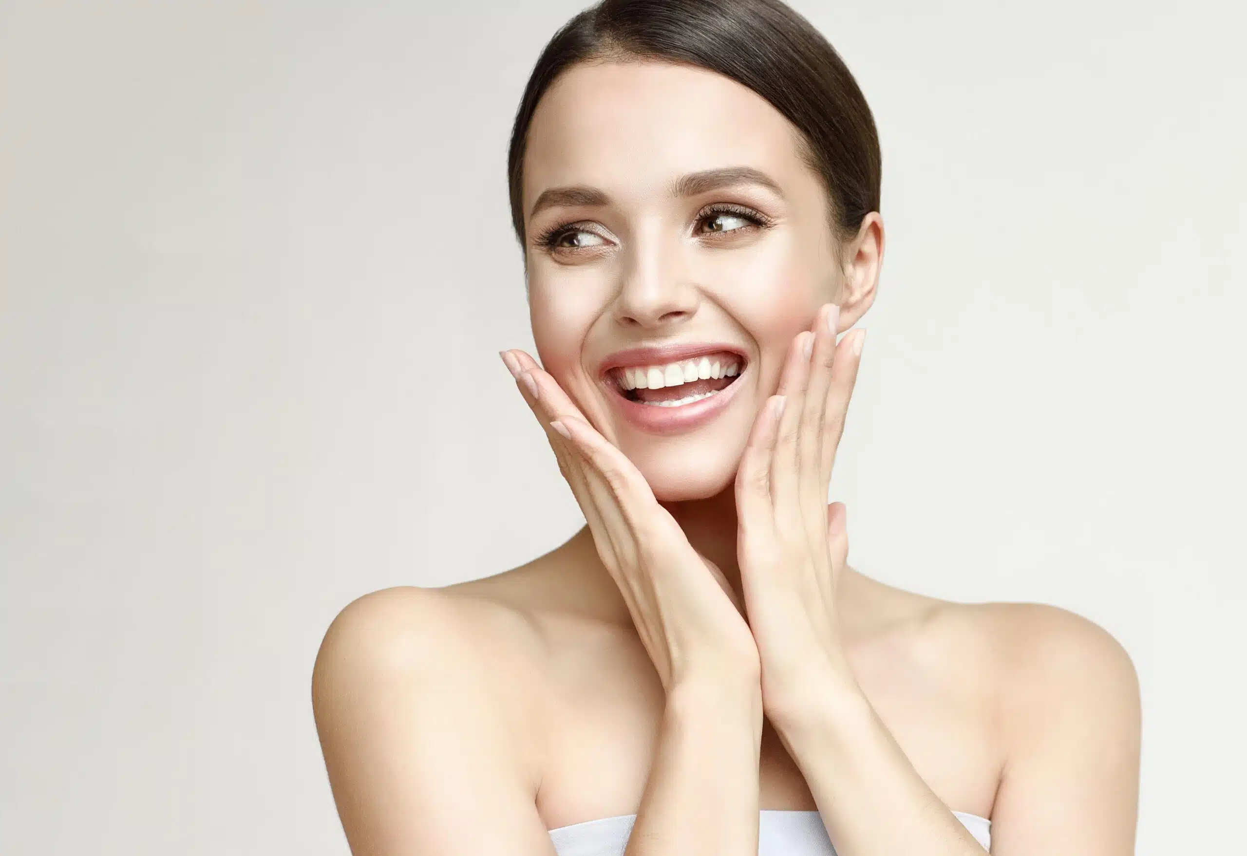 Admiration and happiness on the face of laughing young pretty woman. Beautiful model in looking aside with wide smile, symbolic image of hype. Cosmetology and beauty technologies.